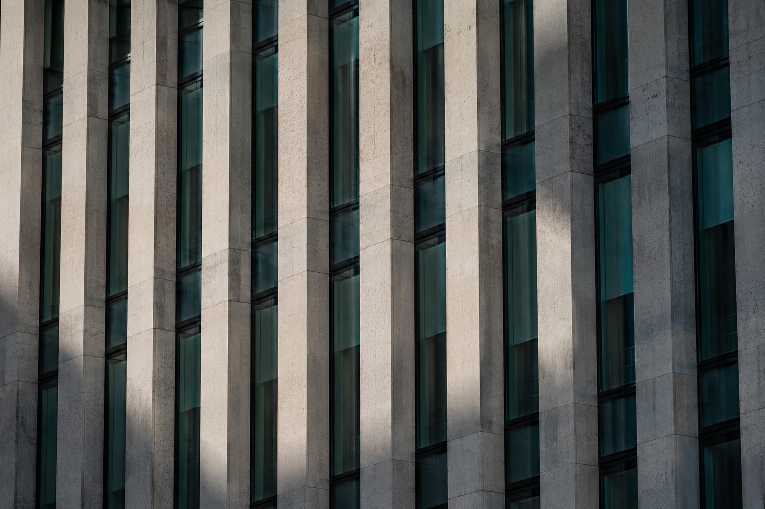Close-up of a modern university building facade with tall windows and stone columns