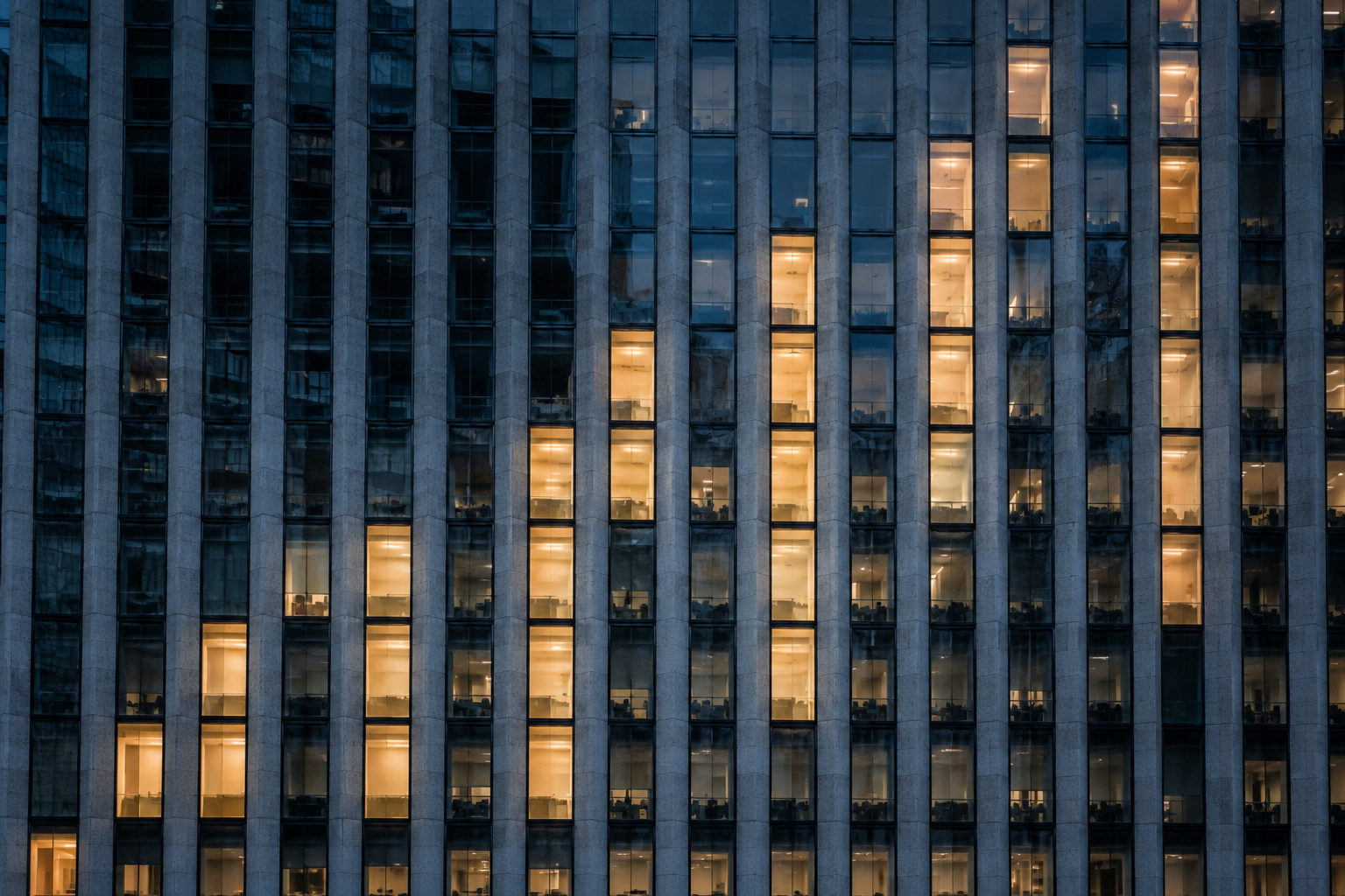 Illuminated office building facade at dusk in a European financial district.